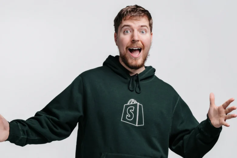 Pria tersenyum lebar mengenakan hoodie hitam dengan logo Shopify.