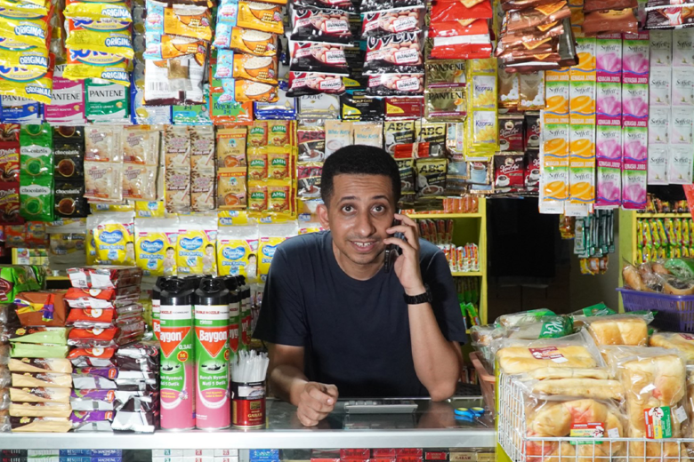 Habib Hussein Ja'far sedang berbicara di telepon di dalam toko swalayan yang penuh barang.