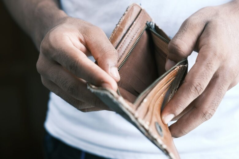 Pria memegang dompet kosong dengan latar belakang buram.