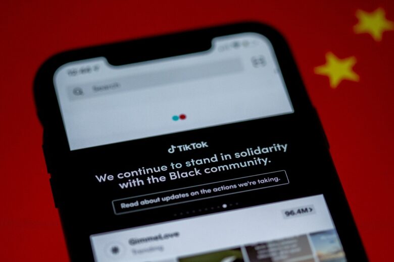 Layar ponsel menampilkan pesan dari TikTok yang mengekspresikan dukungannya terhadap komunitas Black di atas latar belakang bendera China.