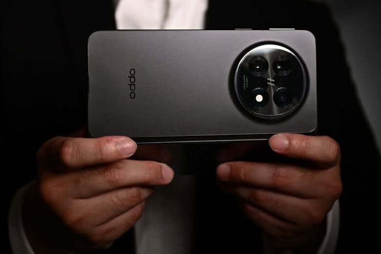 Pria memegang ponsel Oppo Find 5 berwarna abu-abu.