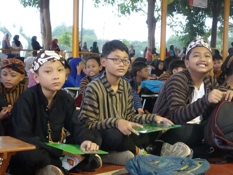 Memperkenalkan Budaya Jawa pada Generasi Muda Sekelompok anak-anak mengenakan pakaian tradisional Jawa, sedang duduk di lantai dengan ekspresi beragam.
