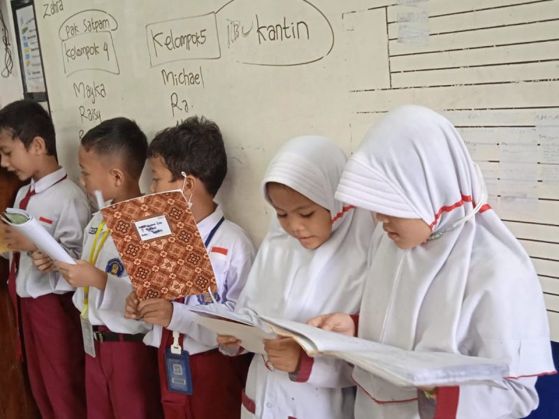 Kegiatan Belajar Bersama di Kelas Anak-anak sedang berkolaborasi membaca di dalam kelas, menunjukkan semangat belajar yang tinggi.