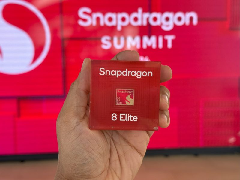 Chip Snapdragon 8 Elite di tangan dengan latar belakang logo Snapdragon.