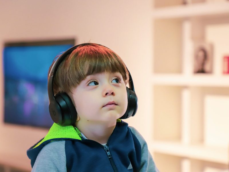 Anak kecil menggunakan headphone sambil mendengarkan musik di ruangan modern