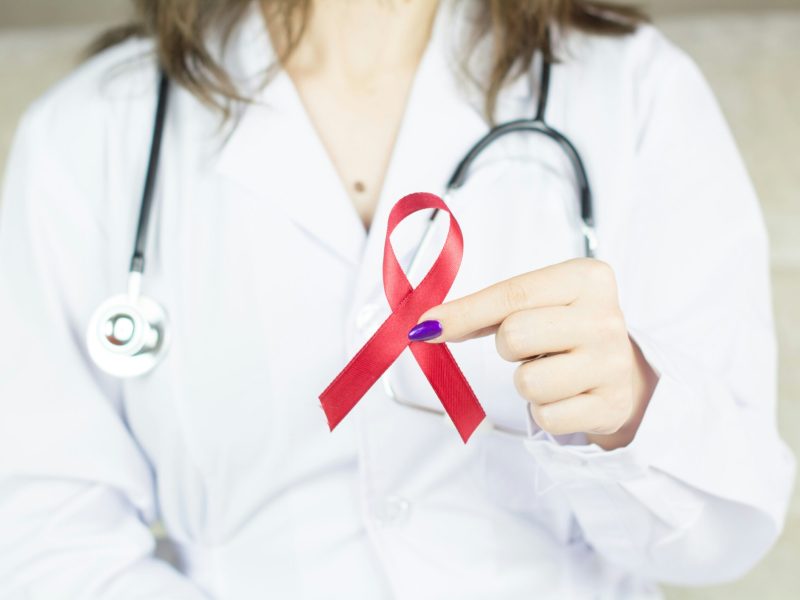 Pita Merah untuk Kesadaran HIV/AIDS Gambar seorang dokter dengan pita merah, simbol kesadaran HIV/AIDS.