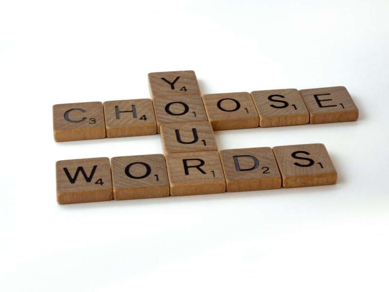 Pilih Kata Anda Gambar close-up papan Scrabble dengan kata-kata "Pilih Kata" yang dieja menggunakan ubin huruf.