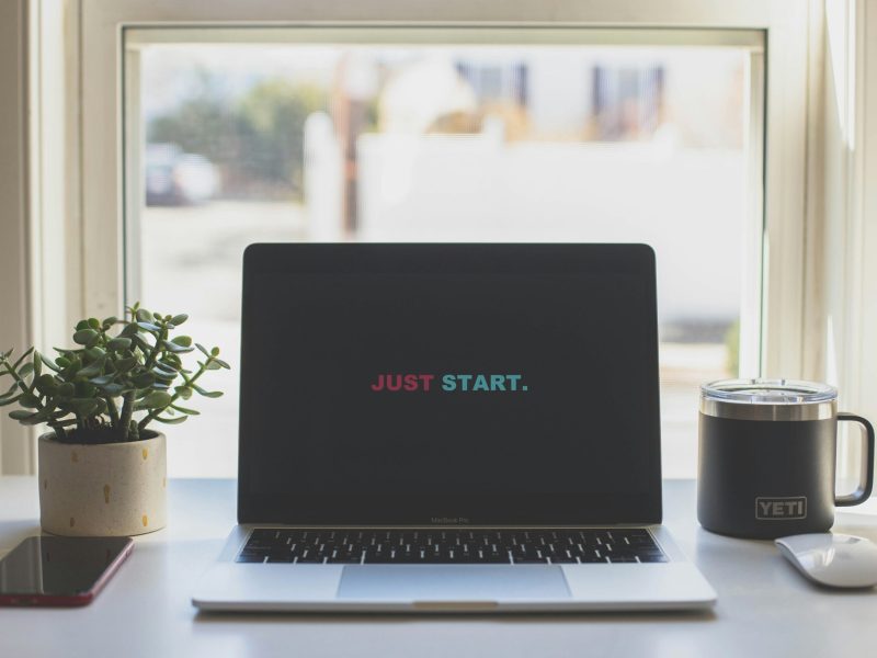 Motivasi untuk Memulai: Layar Laptop dengan Pesan Inspiratif Layar laptop dengan tulisan "JUST START" di tengah dan tanaman hias di sampingnya.