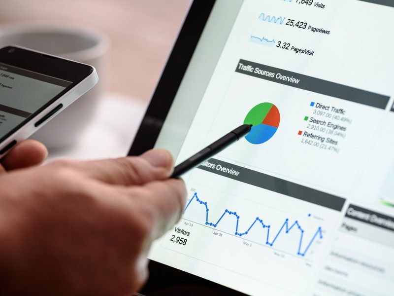 Analisis Data Website Seorang pria sedang menganalisis data di layar komputer. Dia menggunakan stylus untuk menunjuk ke grafik dan bagan yang menampilkan statistik situs web.