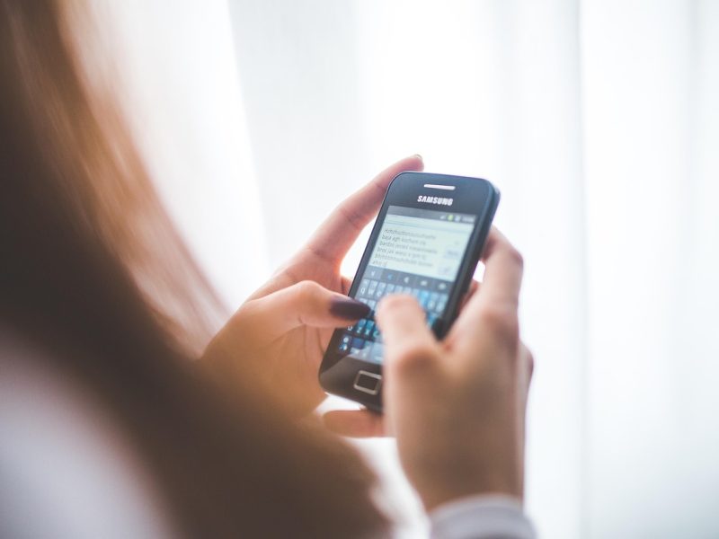 Pemanfaatan AI di Ponsel Wanita sedang mengirim pesan di ponsel Samsung.