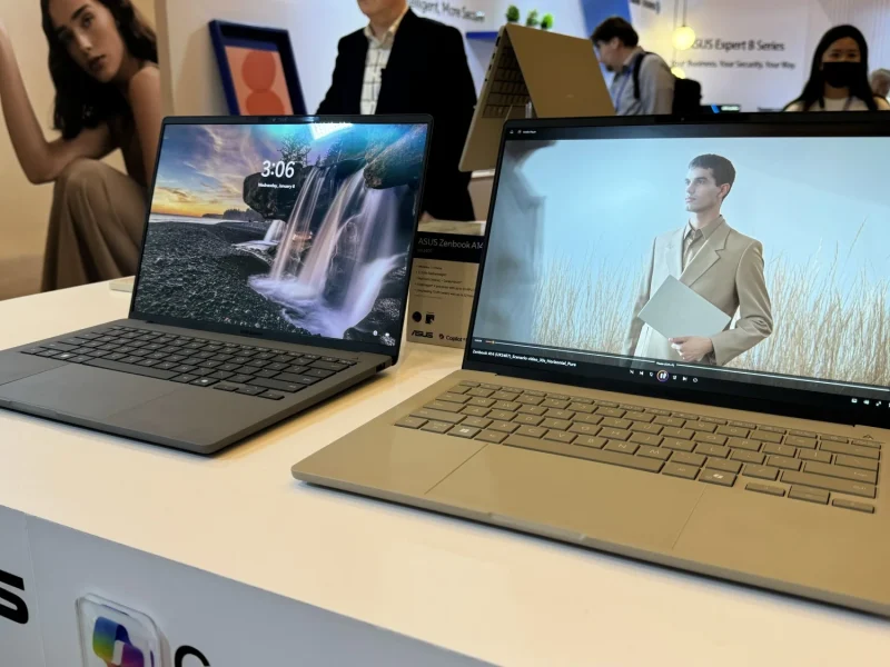 Dua laptop ASUS Zenbook A14 di pameran teknologi, satu menampilkan gambar air terjun dan lainnya menampilkan video seorang model.