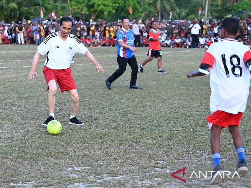 Presiden Joko Widodo bermain sepak bola dengan anak-anak di lapangan.