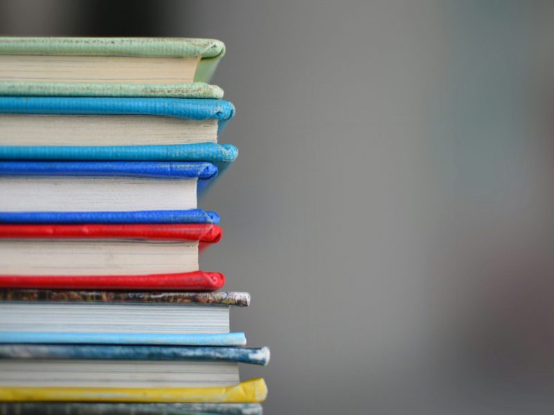 Tumpukan Buku Berwarna Menarik Tumpukan buku dengan cover berwarna hijau, biru, merah, dan kuning yang tersusun rapi