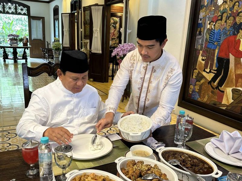 Prabowo Subianto sedang disajikan nasi oleh Kaesang Pangarep dalam suasana makan bersama.