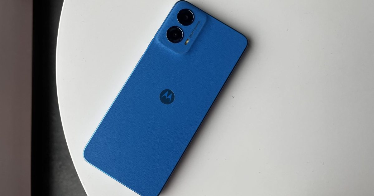 Gambar ponsel Motorola Moto G45 5G berwarna biru diletakkan di atas meja putih