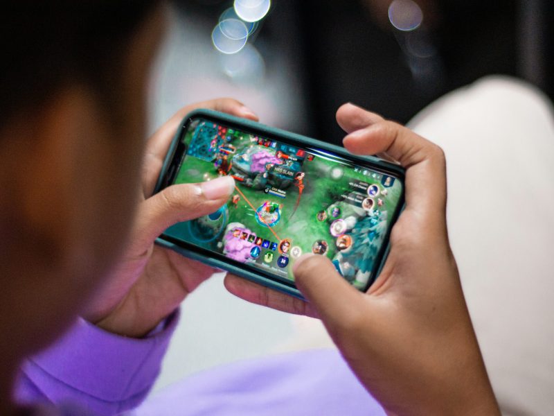 Pengguna bermain game mobile di smartphone dalam suasana yang santai