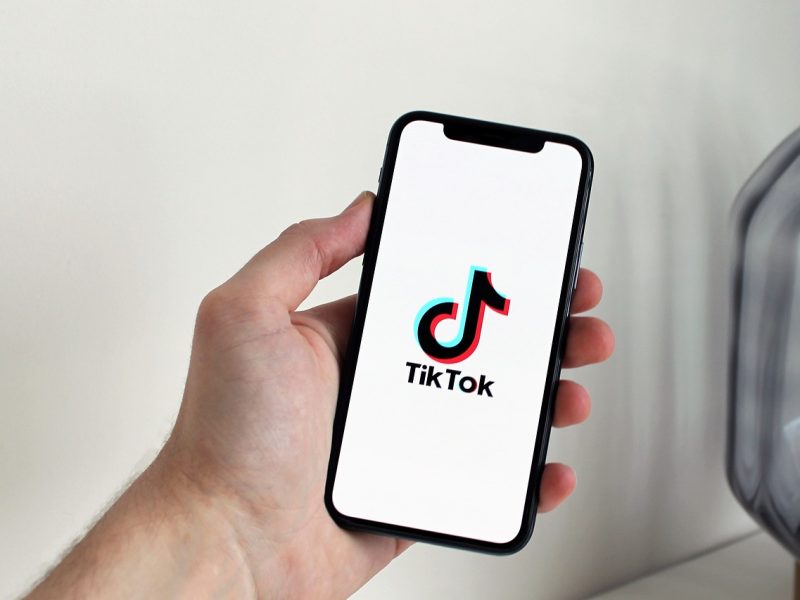 Seseorang memegang smartphone yang menampilkan logo aplikasi TikTok di layar.