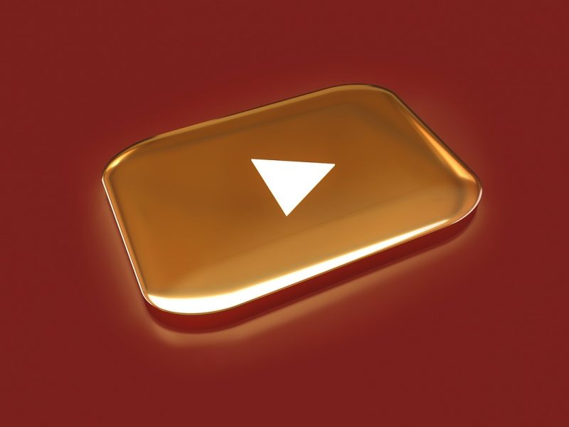 Logo YouTube Gold Play Button di latar belakang merah